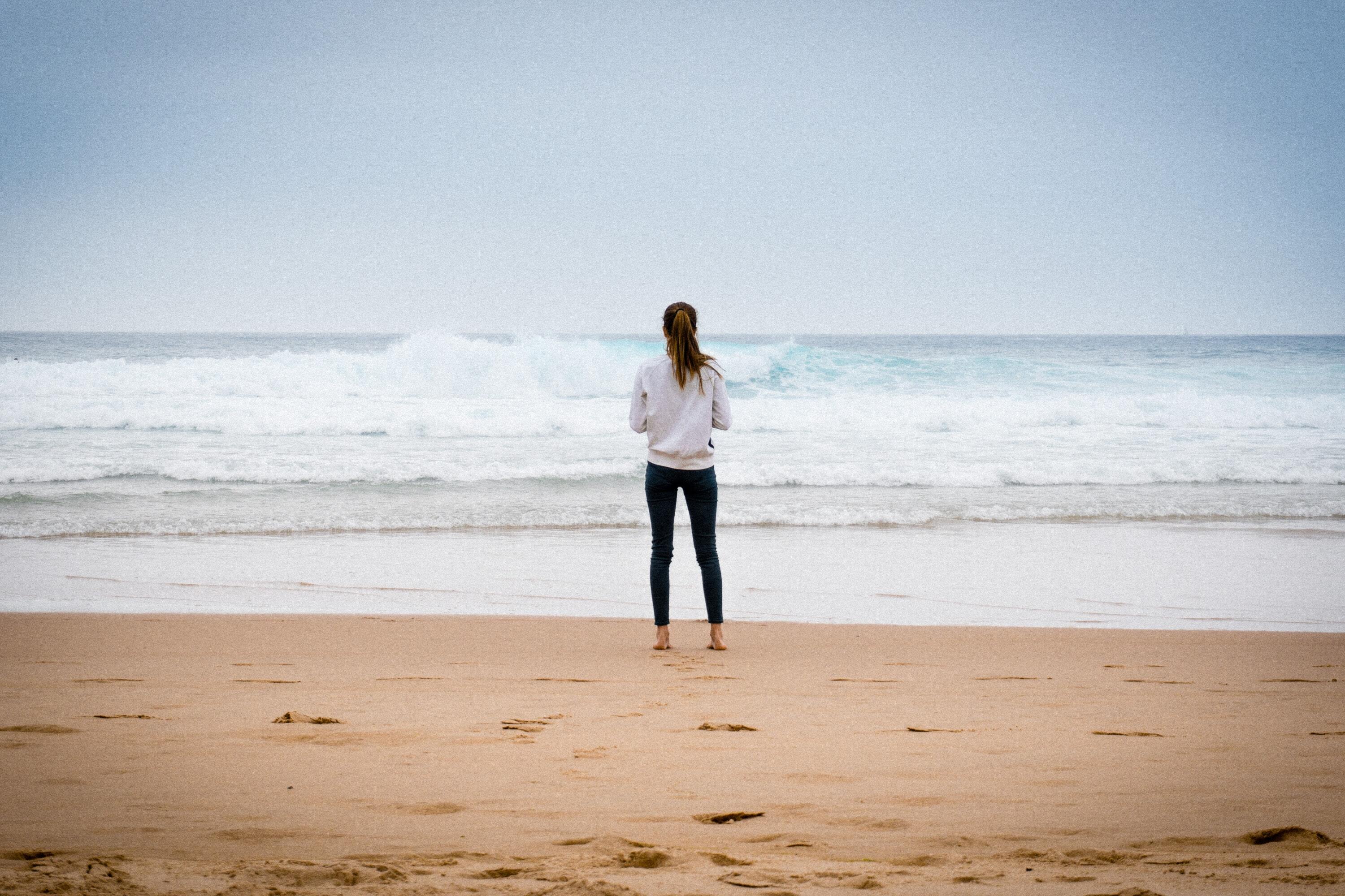 person standing at the beach looking at the water